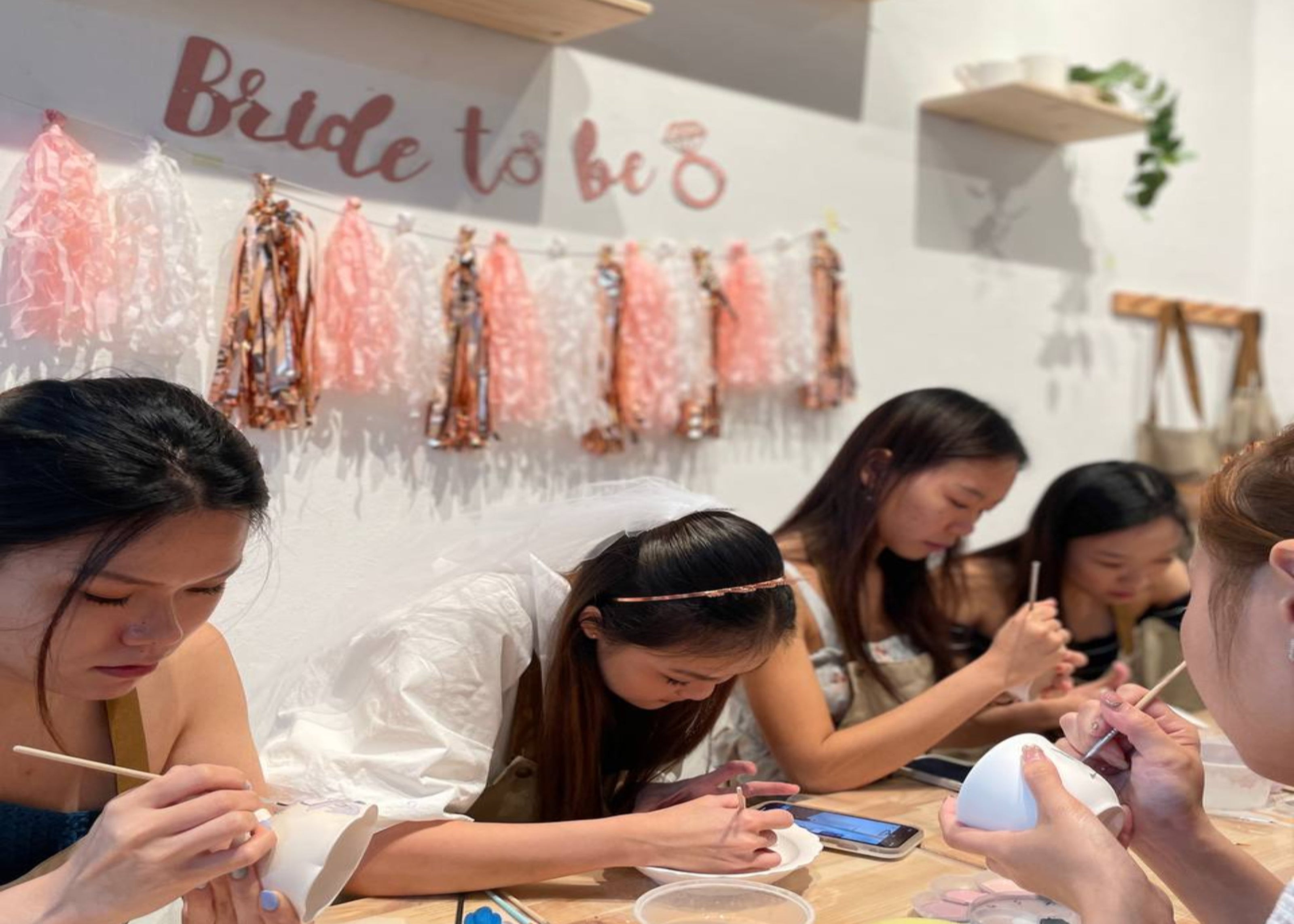 Bride-to-be and her friends enjoying a fun and stress free bachelorette pottery painting party at PotteryPlease in Singapore