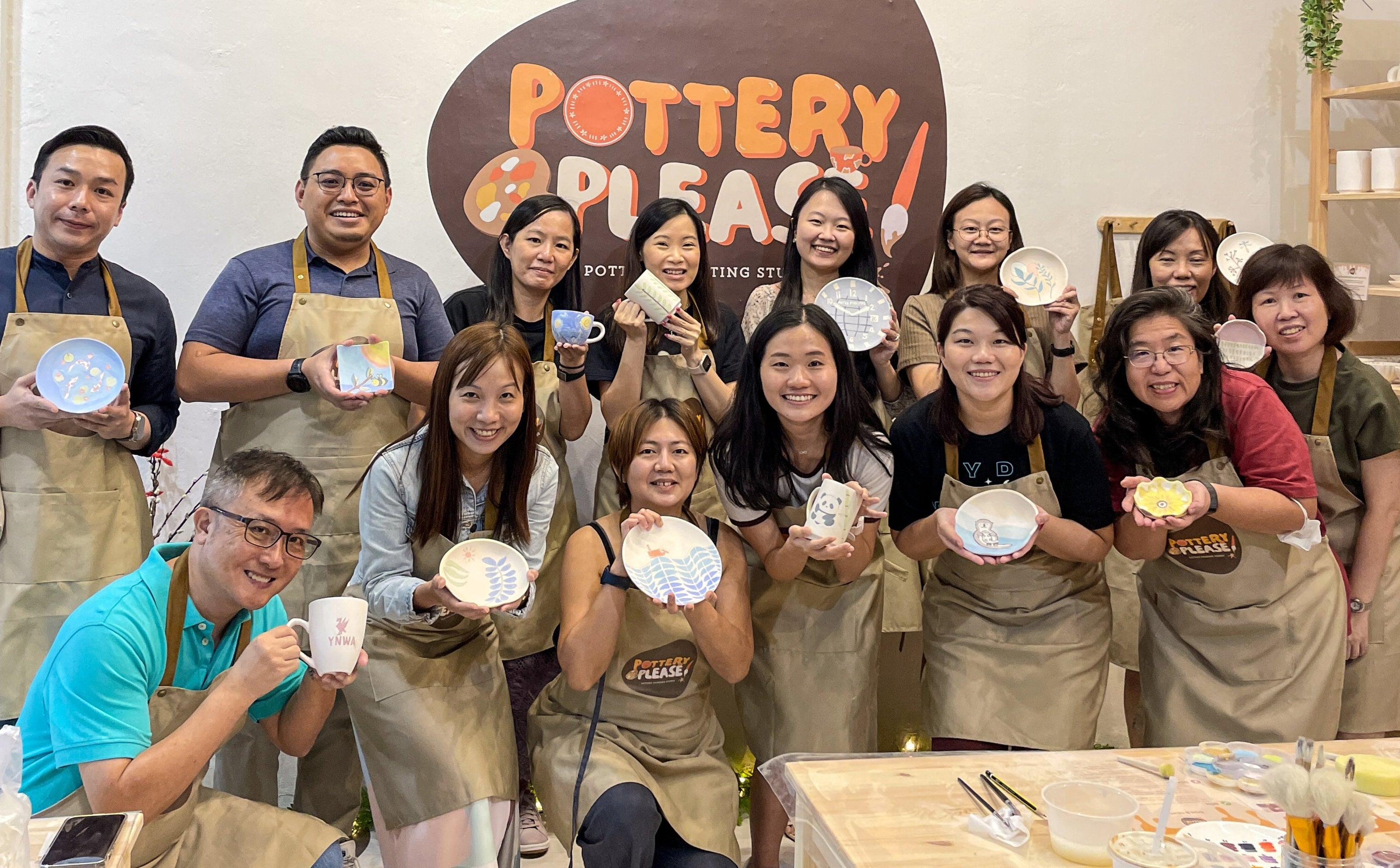 Team bonding during a corporate pottery painting event at PotteryPlease! in Singapore.